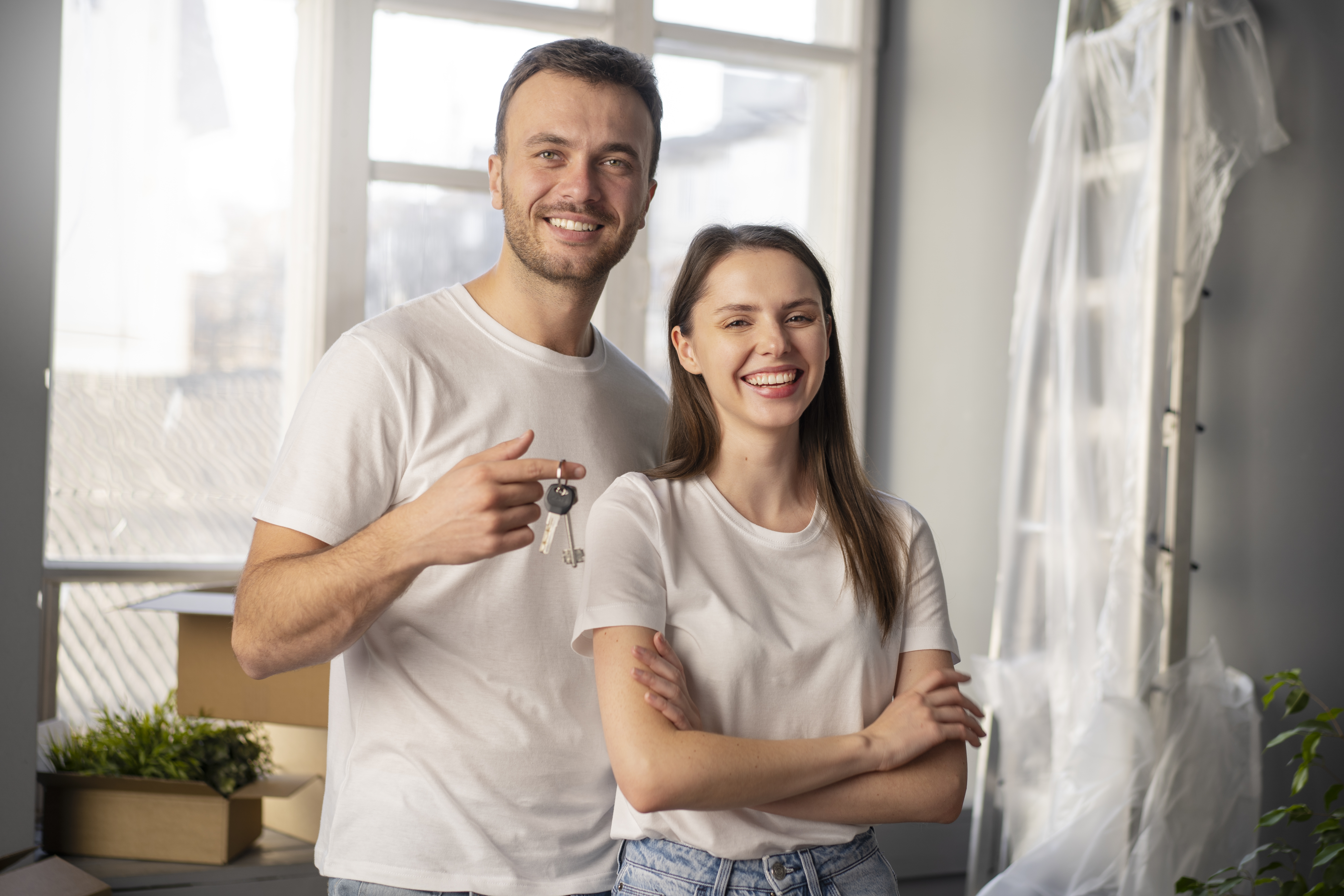 Happy man and women standing in there new home. The man is holding keys