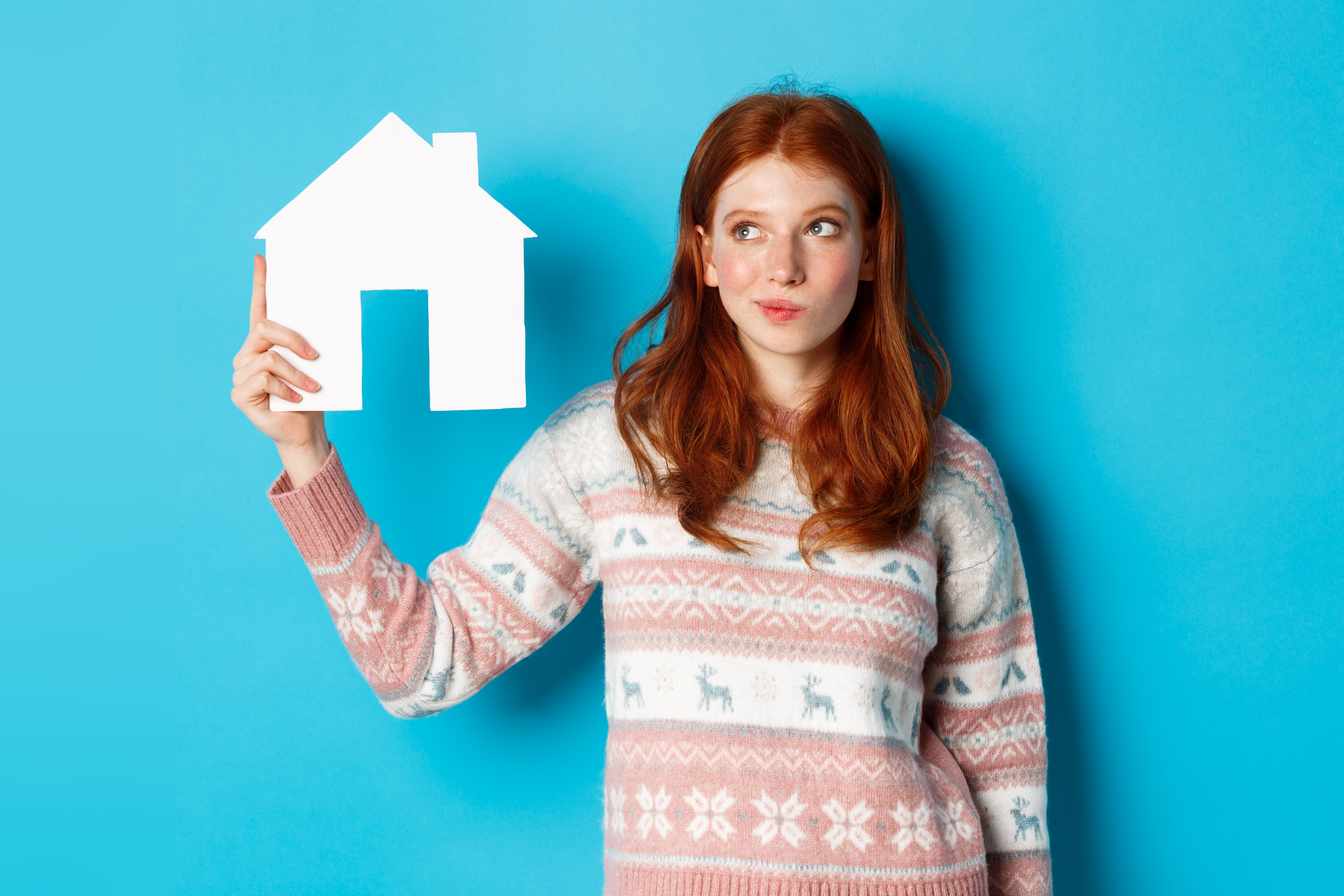 Red haired women holding a white house in the right hand