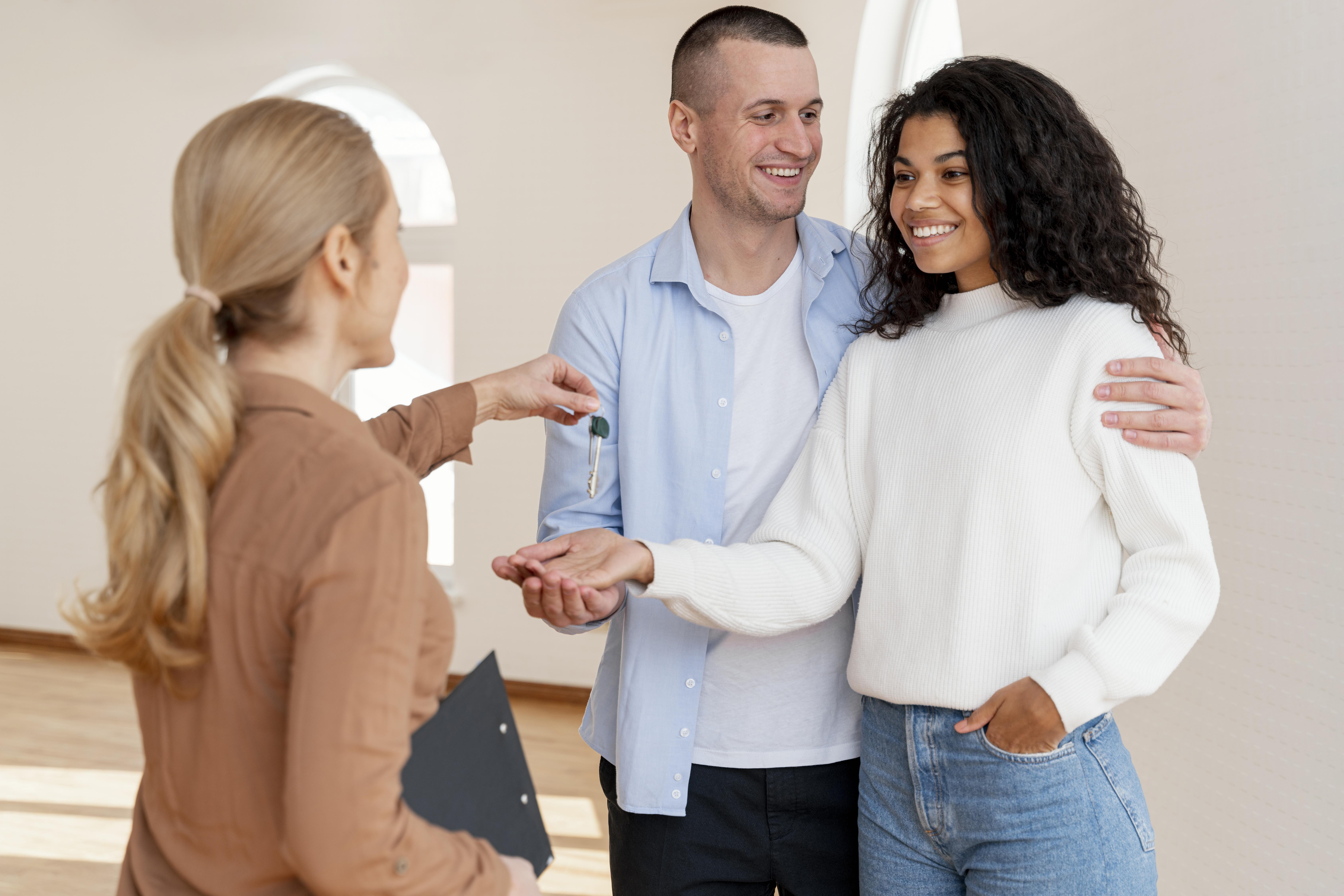 Happy man and women standing in there new home. The man is holding keys